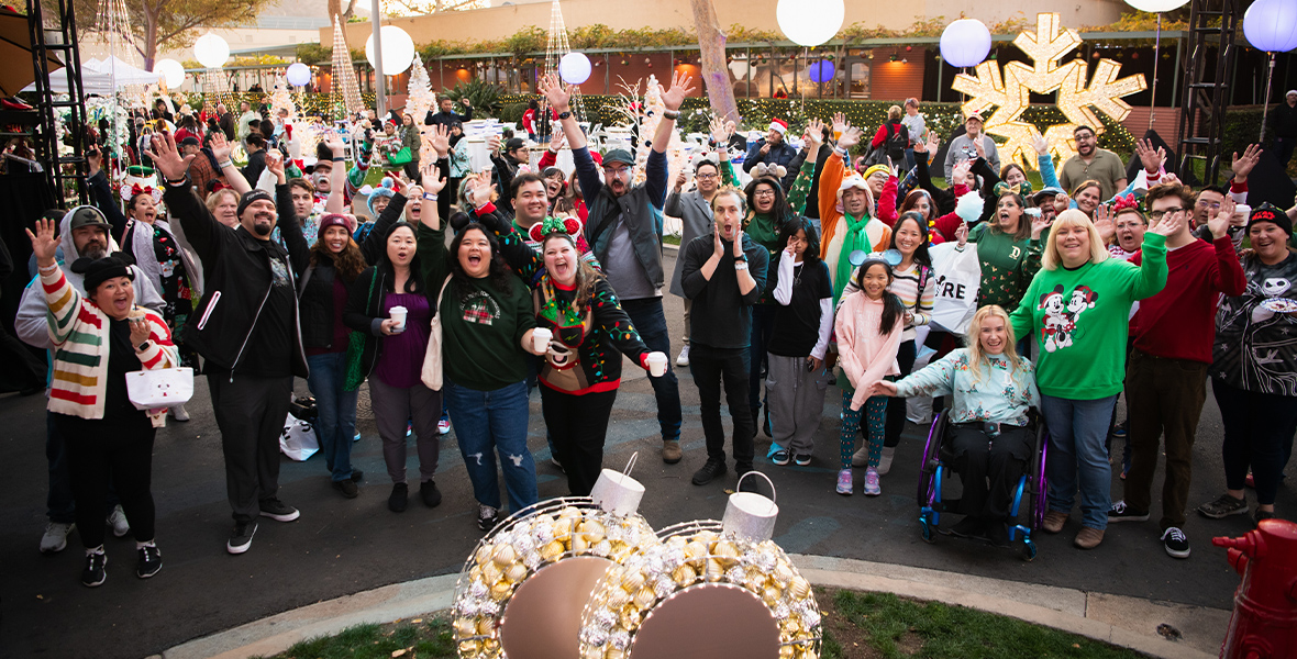 D23 Members cheer in excitement surrounded by festive holiday decorations.