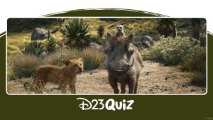 In an image from The Lion King (2019), young Simba (voiced by JD McCrary), a lion cub, walks alongside Pumbaa (voiced by Seth Rogen), a warthog, and Timon (voiced by Billy Eichner), a meerkat perched on Pumbaa's head. The background features rocky terrain, trees, and flowers, with the trio standing on dry, barren ground. In the distance, the landscape becomes lusher and more vibrant.