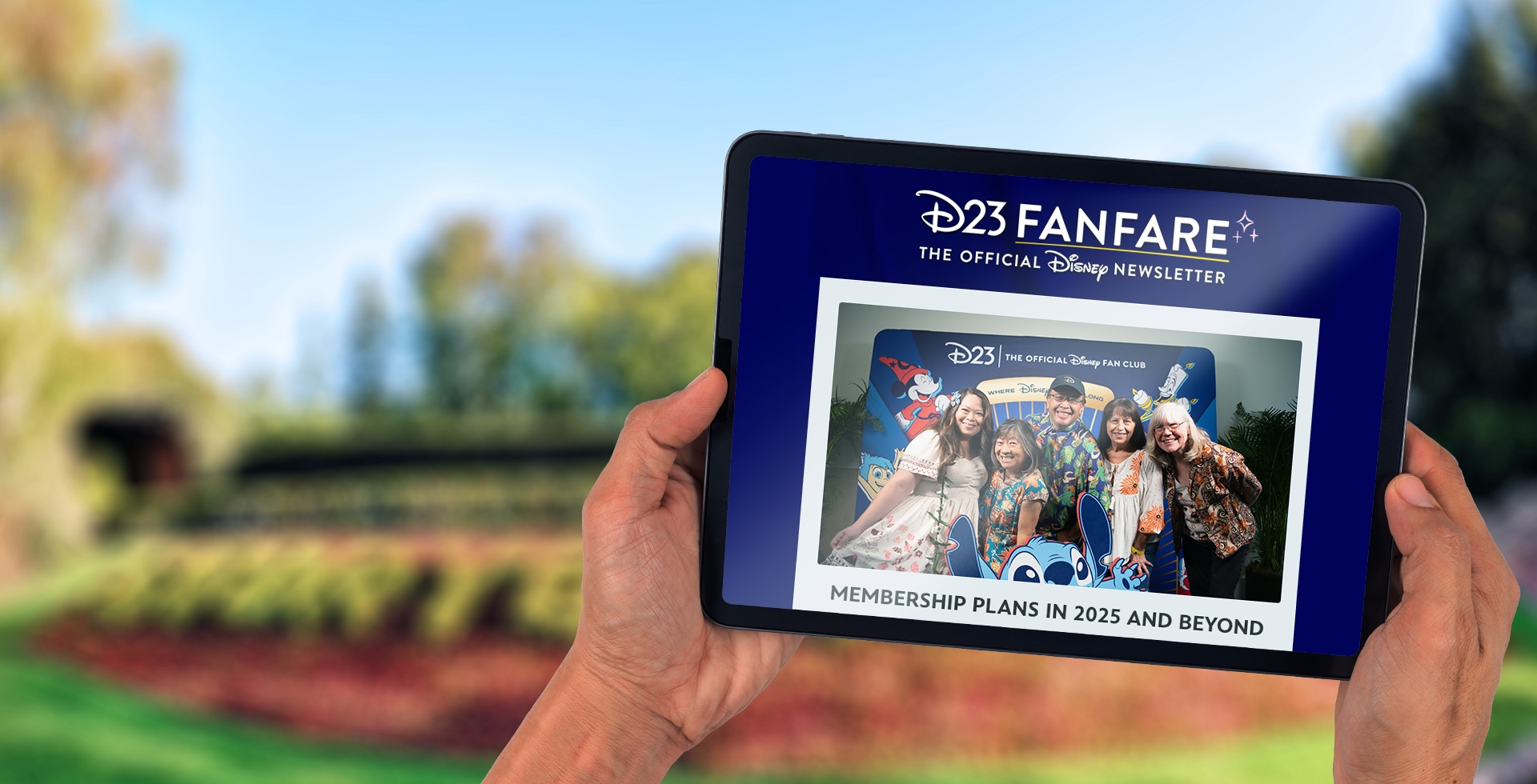 Hands holding a tablet that has D23 FanFare pulled up, getting information on new Membership Plans.