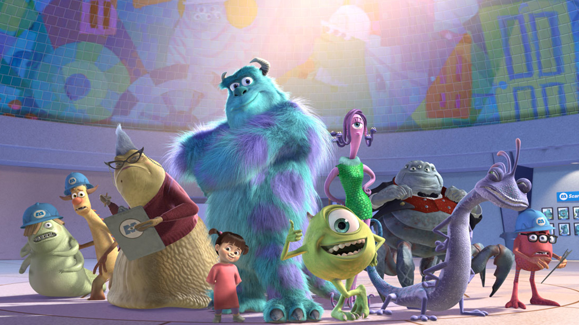 The main characters from Pixar’s Monsters, Inc. posing in front of a colorful mural depicting doors and other monsters. 