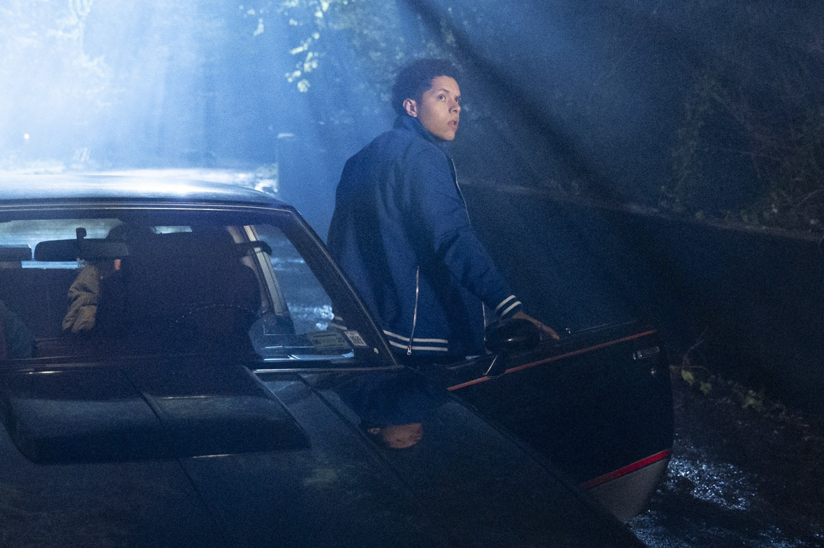 In an image from Goosebumps: The Vanishing, Trey Jimenez (Stony Blyden) is stepping out of a sedan, his back to the audience but looking over his shoulder so we can see his face. He is looking with concern at something offscreen. While it seems to be nighttime, a bright light shines down on Trey and the car.