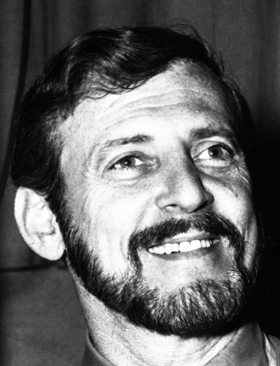 A black-and-white portrait photograph of just the face of actor Paul Winchell, the voice of Tigger. He has dark, neatly groomed hair and a full beard and is looking off to the right with a smile.