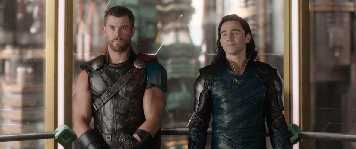 Thor, looking upset, and Loki, smiling, stand side by side in a scene from Thor: Ragnarok.