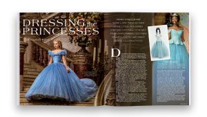 A two-page spread from inside the Disney twenty-three publication for Spring 2025 depicts the first two pages of a story titled Dressing the Princesses. In addition to the text of the story, there are three photos. On the lefthand page is Cinderella (played by Lily James) from the 2015 live-action Disney film, in her blue ball gown, descending the stairs to the castle ballroom. On the righthand page is a photo of Cinderella as portrayed by Brandy in the 1997 TV movie for ABC. She is wearing her blue ball gown and a tiara. The third photo, inset beside the photo of Brandy, is an image of Brandy&rsquo;s gown, wig, and tiara, modeled by a faceless white mannequin.
