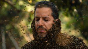 Hundreds of bees cover David Blaine's neck and upper torso.