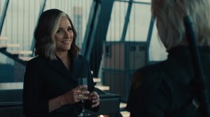 Valentina Allegra De Fontaine wearing a dark suit and holding a glass of champagne while talking to Yelena Belova.
