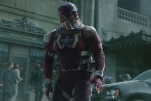 In an image from Marvel’s Thunderbolts* The New Avengers, Alexei Shostakov / Red Guardian (David Harbour) is in his Super Hero suit and standing in smoky downtown street. He’s looking over his shoulder at something off camera to the right. There are bystanders behind him, looking in the same direction, and there is a car behind him to the right.