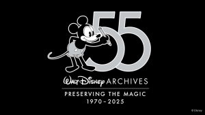 The logo for the Walt Disney Archives 55th anniversary, set on a black background, features a 1920s-era, black-and-white-style Mickey Mouse in gray shorts holding a pencil next to a large number “55” set in gray. Below these icons is a logo reading “Walt Disney Archives” in white. Below it is a white line separating the slogan “Preserving the Magic,” with “1970–2025” on the bottom line.
