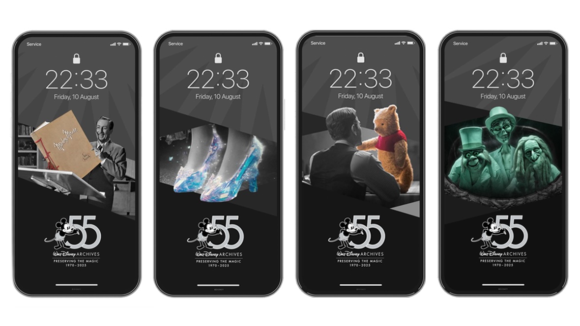 A series of four mobile device wallpapers is mocked up, each featuring an historical image set in grayscale with a single element (representing an object from the Walt Disney Archives collection) in color. Each mobile device mockup features a “lock” symbol on top with the large time set to 22:33. On the bottom of each graphic is the Walt Disney Archives 55th anniversary logo, featuring a 1920s-era, black-and-white-style Mickey Mouse in gray shorts holding a pencil next to a large number “55” set in gray. Below these icons is a logo reading “Walt Disney Archives” in white. Below the Archives logo is a white line separating the slogan “Preserving the Magic,” with “1970–2025” on the bottom line. From left to right, the represented images and assets are: a grayscale Walt Disney holding a large, tan-colored oversized book (titled “Mickey Mouse: His Book”) from the Disneyland television series; a color pair of glass slippers representing the live-action film Cinderella (2015); a color Winnie the Pooh doll, with a live-action adult Christopher Robin in grayscale (from Christopher Robin, 2018); and three green-hued Hitchhiking Ghosts figures from the Haunted Mansion attraction at Walt Disney World Resort, seated in a grayscale Doom Buggy ride vehicle and set in an ornate mirror frame. 