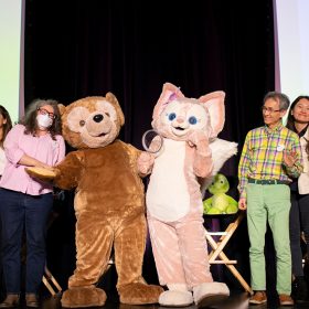 From left to right, D23’s Jessica McDonald, WDI’s Eva Lee, Laura West, Charlie Watanabe, Xiao Qing Chen, and Disney Live Entertainment’s Trevor Rush pose onstage with Duffy and LinaBell performers.