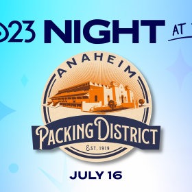 A promotional image for D23 Night at the Anaheim Packing District on July 16, 2025. The background is blue, cyan, and indigo with darker sparkles. An orange and blue logo at the center of the image, for the Anaheim Packing District, features a shaded picture of the location itself around distinct, curved text reading “Anaheim Packing District, est. 1919. Above the logo are the words “D23 Night at the: below the logo, it reads “July 16.”