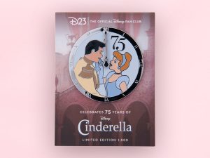 A pin celebrating the 75th anniversary of Cinderella. Cinderella, wearing her iconic blue dress, is looking up at Prince Charming, smiling. They are positioned upon a clock façade that is pointing at midnight. There is a big number 75 above Cinderella’s head.