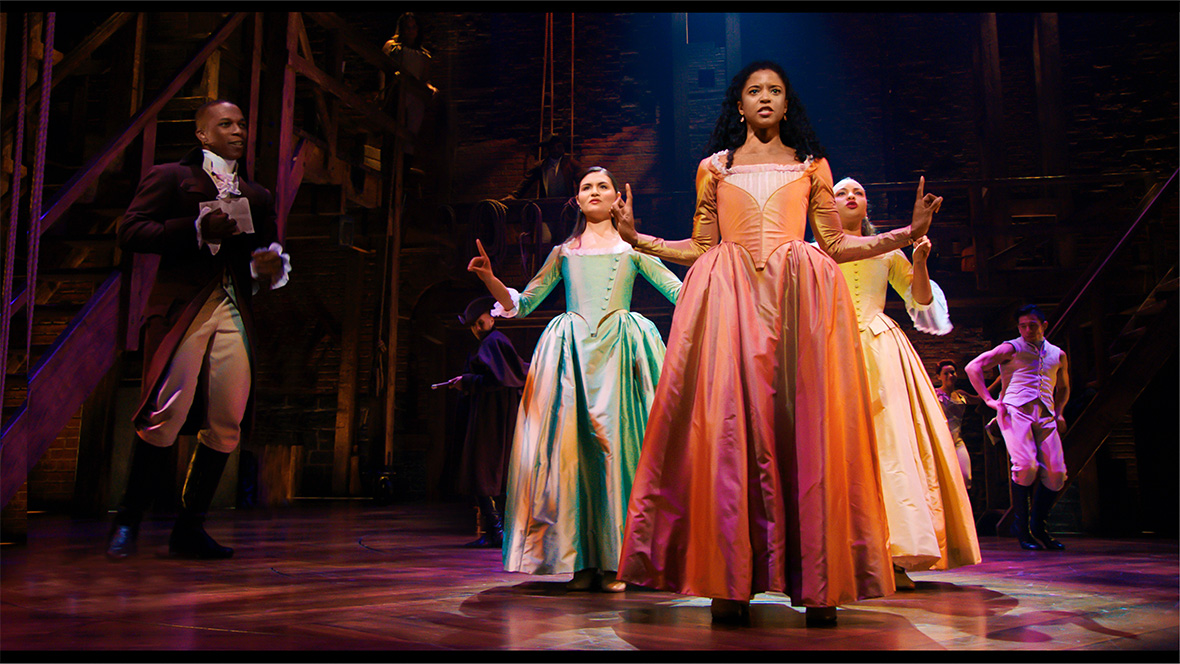 The Schuyler sisters from the original Broadway cast of Hamilton dancing together with their arms out.