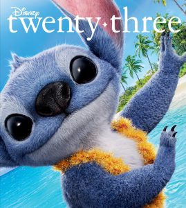 Stitch smiles playfully in a close-up shot on the beach, wearing a fluffy yellow lei, with bright blue ocean water and palm trees in the background. The image is the cover of the Summer 2025 issue of Disney twenty-three.