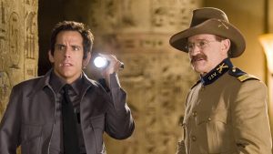 Security guard Larry Daley and Theodore Roosevelt Night at the Museum. Daley is holding a flashlight and wearing a grey security guard uniform. Roosevelt is in a brown military uniform holding a rifle.