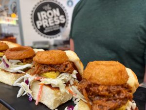 Loco Moco Sliders from The Iron Press. Pictured are sliders with an onion ring, coleslaw, and pulled pork. 