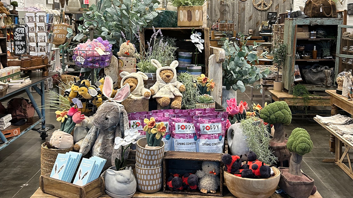 Gold Member Offer: 23% Off Merchandise at Sugarboo & Co. in Disney Springs, FL A wooden display within the Sugarboo & Co. store. The products on display are Teddy Bears in sweaters (with bunny ears) as well as various other plushies. Some of the plushies include ladybugs, rabbits, and flowers in pots. In addition to this, there are some actual plants.