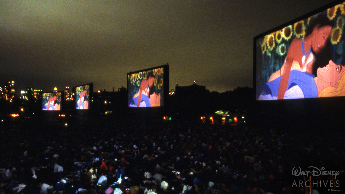 Four giant screens illuminate the night with Pocahontas and John Smith lying in a field of sunflowers during the premiere of Pocahontas.