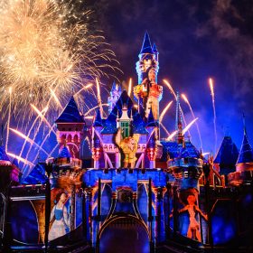 Photo of Wondrous Journeys nighttime spectacular at Disneyland Resort. Sleeping Beauty Castle is lit up with projections of Belle from Beauty and the Beast, Hercules from Hercules, and Quasimodo from The Hunchback of Notre Dame. There are several golden fireworks in the sky behind the castle.