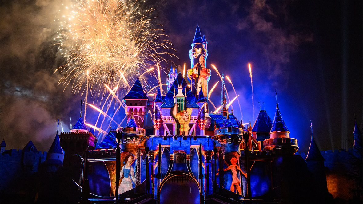 Photo of Wondrous Journeys nighttime spectacular at Disneyland Resort. Sleeping Beauty Castle is lit up with projections of Belle from Beauty and the Beast, Hercules from Hercules, and Quasimodo from The Hunchback of Notre Dame. There are several golden fireworks in the sky behind the castle.