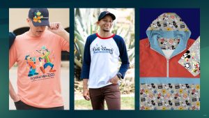 Three-panel image showcasing Disney-themed apparel: left, a man wears a coral Destination D23 t-shirt featuring Goofy and Max along with a navy cap embroidered with Mickey Mouse; center, a man smiles in a white and navy Walt Disney Imagineering baseball tee with red collar; right, a red and blue hooded jacket with a lining patterned in Minnie Mouse, film icons, and popcorn, alongside a matching pouch.