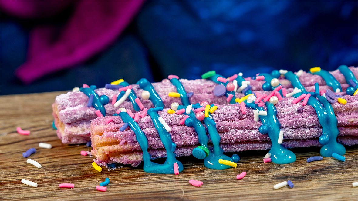 Collage with two images of churros. On the left, a Banana Split Churro rolled in chocolate sugar and topped with banana sauce, vanilla saucer, and a cherry. On the right, a 70th Celebration Churro rolled in ube sugar and topped with marbles blue raspberry icing drizzle and sprinkles.