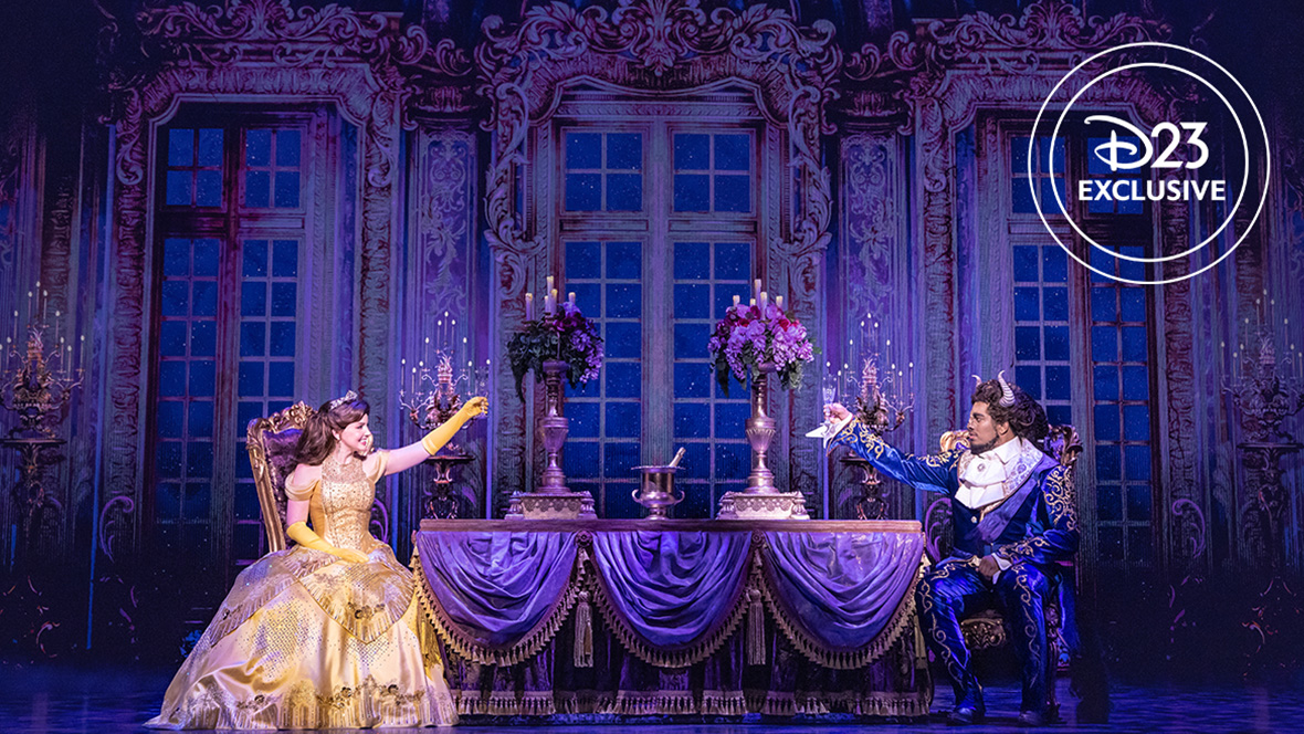 Kyra Belle Johnson as Belle and Fergie L. Philippe as Beast in an exclusive photo from Disney Theatrical Group’s North American Tour of Beauty and the Beast. They are seen in the dining room of the Beast’s castle; Belle is wearing her iconic yellow ball gown. Both are lifting glasses.
