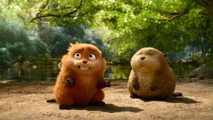 (L-R) A robotic beaver, imbued with the human consciousness of Mabel (voiced by Piper Curda) sits on the bank of a pond with a beaver, which is lighter in color. The robotic beaver is looking at something off-screen, while the other has its eyes closed. Green foliage and a dam are in the background.