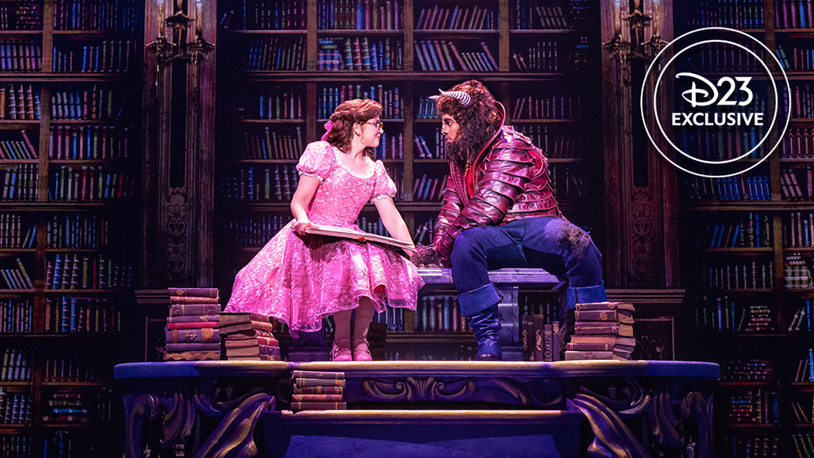 Kyra Belle Johnson as Belle and Fergie L. Philippe as Beast in an exclusive photo from Disney Theatrical Group’s North American Tour of Beauty and the Beast. They are sitting side by side in the Beast’s library; Belle is wearing a pink dress and is wearing glasses, and has a book open on her lap.CAPTION: Kyra Belle Johnson as Belle (left) and Fergie L. Philippe as Beast (right) in an exclusive photo 