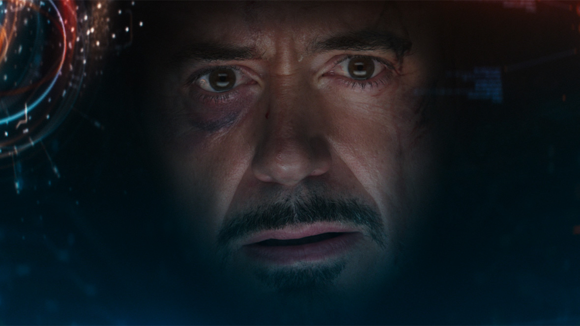 Closeup image of Tony Stark’s face from the Marvel Cinematic Universe. He has a cut on is left eyebrow and is surrounded by visuals made by his AI assistant, F.R.I.D.A.Y., on the inside of his Iron Man suit.
