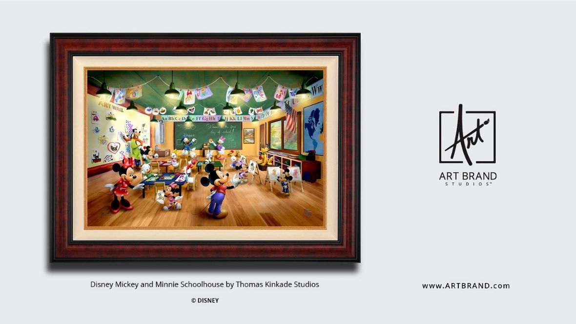 A framed Disney artwork showing Mickey Mouse, Minnie Mouse, and other Disney characters in a colorful classroom setting. The scene depicts the characters as students and teacher in a schoolhouse with wooden floors, green chalkboard, hanging lights, and educational decorations on the walls. The artwork is titled 'Disney Mickey and Minnie Schoolhouse by Thomas Kinkade Studios' and is presented by Art Brand Studio.