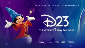 A promotional image for D23: The Ultimate Disney Fan Event, taking place on August 14, 15, and 16, 2026, in Anaheim, California. Sorcerer Mickey—in a red robe and a pointed blue hat with stars and moons—smiles and stands prominently on the left side of the image with his arms raised, looking at the viewer. The event logo is spotlighted on the right side of the image; in the background are visuals resembling searchlights and the outline of a castle. Toward the bottom of the image are the logos for Disney, Pixar, Marvel, Star Wars, and National Geographic. The image is dominated by jewel tones of purple and blue, evoking a sense of magic and sophistication.