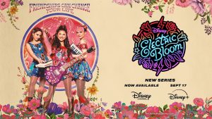 From left to right, Jade, Posey, and Tulip pose in key art for the comedy series Electric Bloom. Jade is wearing a blue floral dress and playing the piano. Posey is wearing a red floral dress and a matching jacket and playing the guitar. Tulip is wearing a red and blue floral outfit and holding a MIDI in her arm. The key art also includes the tagline and premiere details.