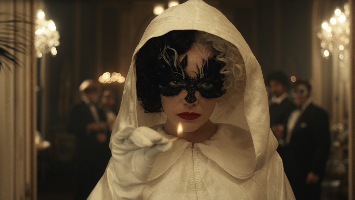 Cruella De Vil (played by Emma Stone) wearing a white hooded clock and a black masquerade mask, holding a lit match in Cruella