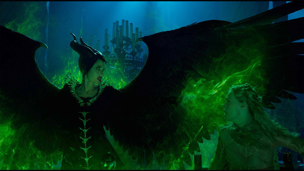Maleficent (played by Angelina Jolie) spreading her wings and encasing herself in green fire in Maleficent: Mistress of Evil