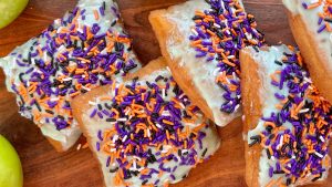 "Caramel Apple Beignet" is a seasonal treat topped with candied apple icing, caramel drizzle, and spooky sprinkles.