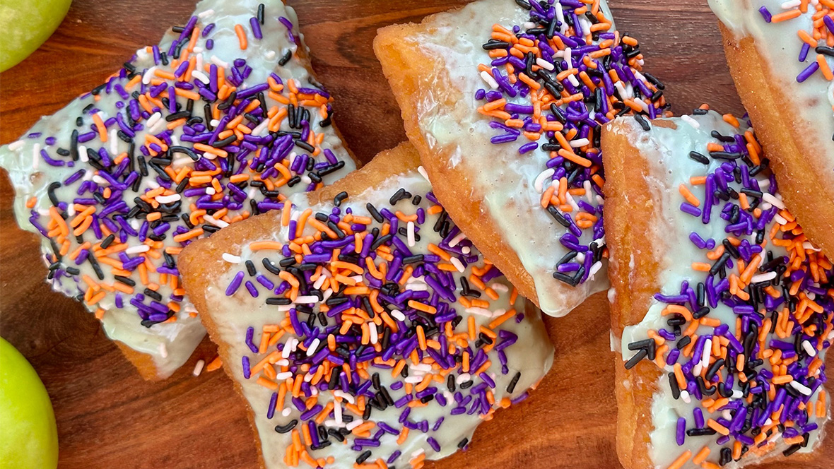 "Caramel Apple Beignet" is a seasonal treat topped with candied apple icing, caramel drizzle, and spooky sprinkles.