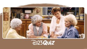 The four roommates from The Golden Girls sit together at the kitchen table. (From left to right) Sophia wears a yellow robe, Dorothy wears a pink shirt and gray scarf, Blanche wears a white dress, and Rose wears a blue robe. Rose is talking and the other women are looking at her intently.