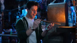 Justin Russo (played by David Henrie) holding a wizard’s wand in a darkened room in front of a glowing box on Wizards Beyond Waverly Place.