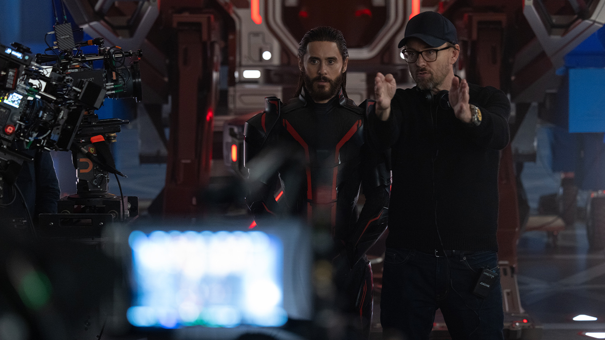 In a behind-the-scenes image from Disney’s Tron: Ares, Jared Leto as Ares (left) is standing next to director Joachim Rønning on set. A large camera rig is seen on the left and in the foreground; Leto is looking at it, and Rønning is gesturing to it. 