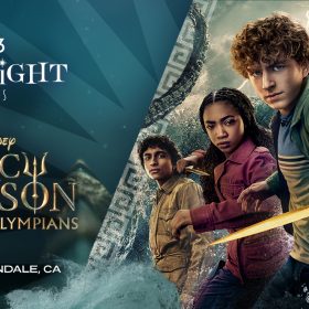 Promotional image for the D23 Spotlight Series featuring Disneys Percy Jackson and the Olympians, showing three characters (from left to right: Grover, Annabeth, and Percy) in action poses with Percy holding a gold sword. The trio is set against a dramatic stormy background with swirling clouds and water. Text at the bottom notes the event will take place December 5 in Glendale, CA.