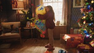 A still from A Disney Holiday Short: Best Christmas Ever, directed by Taika Waititi and featuring the voice of Disney Legend John Goodman. In it, a little girl is hugging a doodle that has come to life.