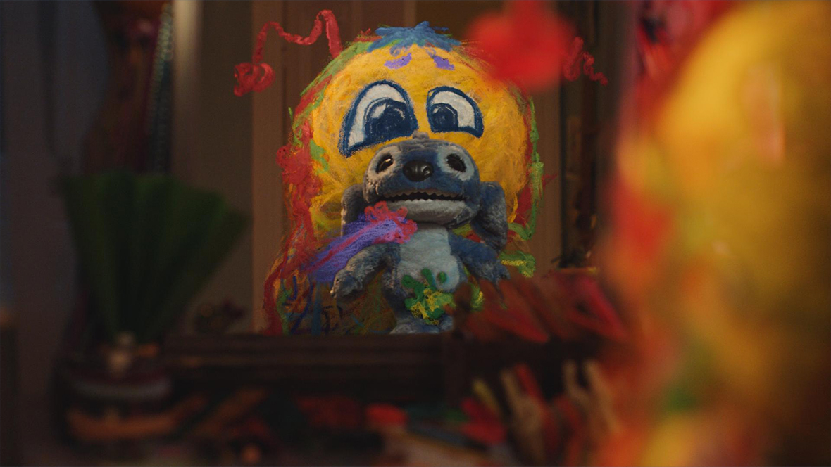 A still from A Disney Holiday Short: Best Christmas Ever, directed by Taika Waititi and featuring the voice of Disney Legend John Goodman. In it, a doodle that has come to life is holding a Stitch plush.
