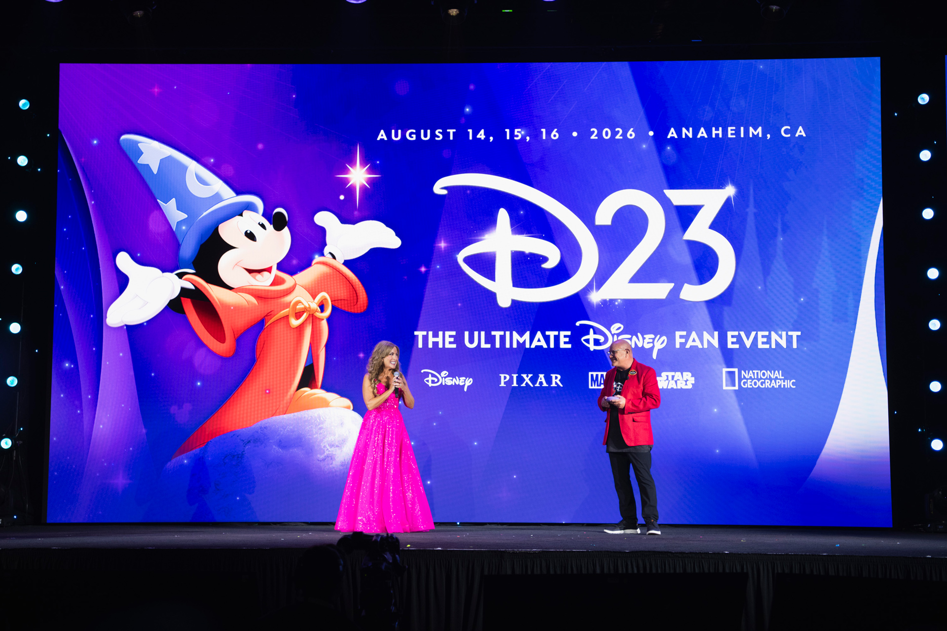 from Destination 23 2025 at Walt Disney World Resort, including Disney Legend Jodi Benson and Head of D23 Michael Vargo on stage in front of the logo for D23: The Ultimate Disney Fan Event 2026