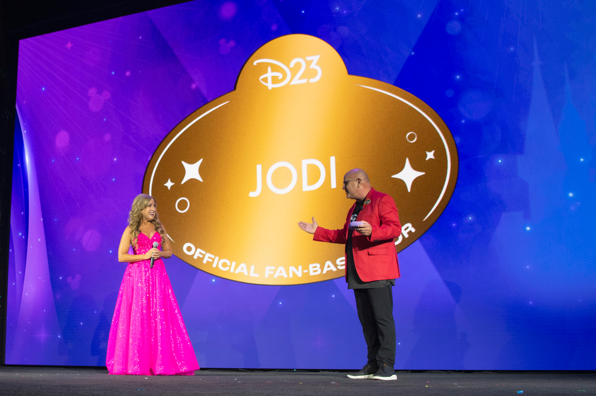 An image of Disney Legend Jodi Benson and Head of D23 Michael Vargo on stage at Destination D23 2025, as Vargo is presenting Benson with the title &ldquo;D23 FAN-bassador.&rdquo;