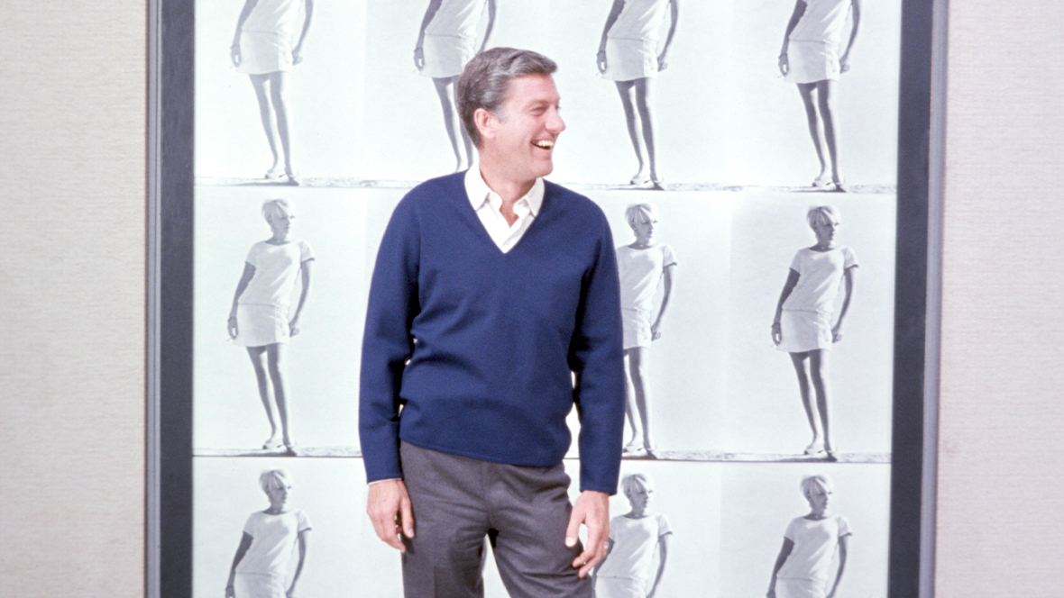 A promotional image of Disney Legend Dick Van Dyke from 1968’s Never a Dull Moment. Van Dyke is standing in front of a large painting in a museum-style setting.
