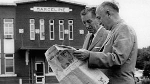 A black and white photo showcases Walt and Roy Disney walking along the Depot (now the Walt Disney Hometown Museum) in 1956; the Depot displays the name &ldquo;Marceline&rdquo; on it. Roy is showing a newspaper to Walt, the cover story of which is about the Walt Disney Studios.