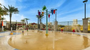 Outdoor splash pad with colorful water features and spray fountains at Drury Plaza Hotel Orlando &ndash; Disney Springs Area, surrounded by palm trees.