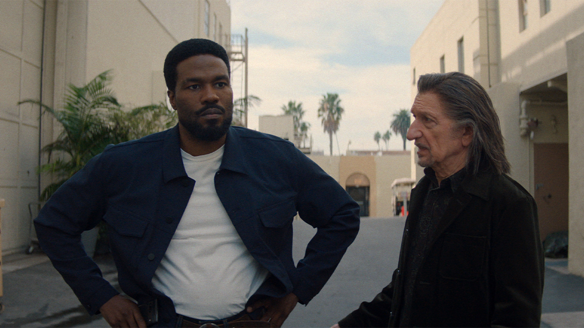 In a still from Marvel Television’s Wonder Man, Simon Williams (Yahya Abdul-Mateen II), left, and Trevor Slattery (Sir Ben Kingsley), right, are standing on a studio backlot talking.
