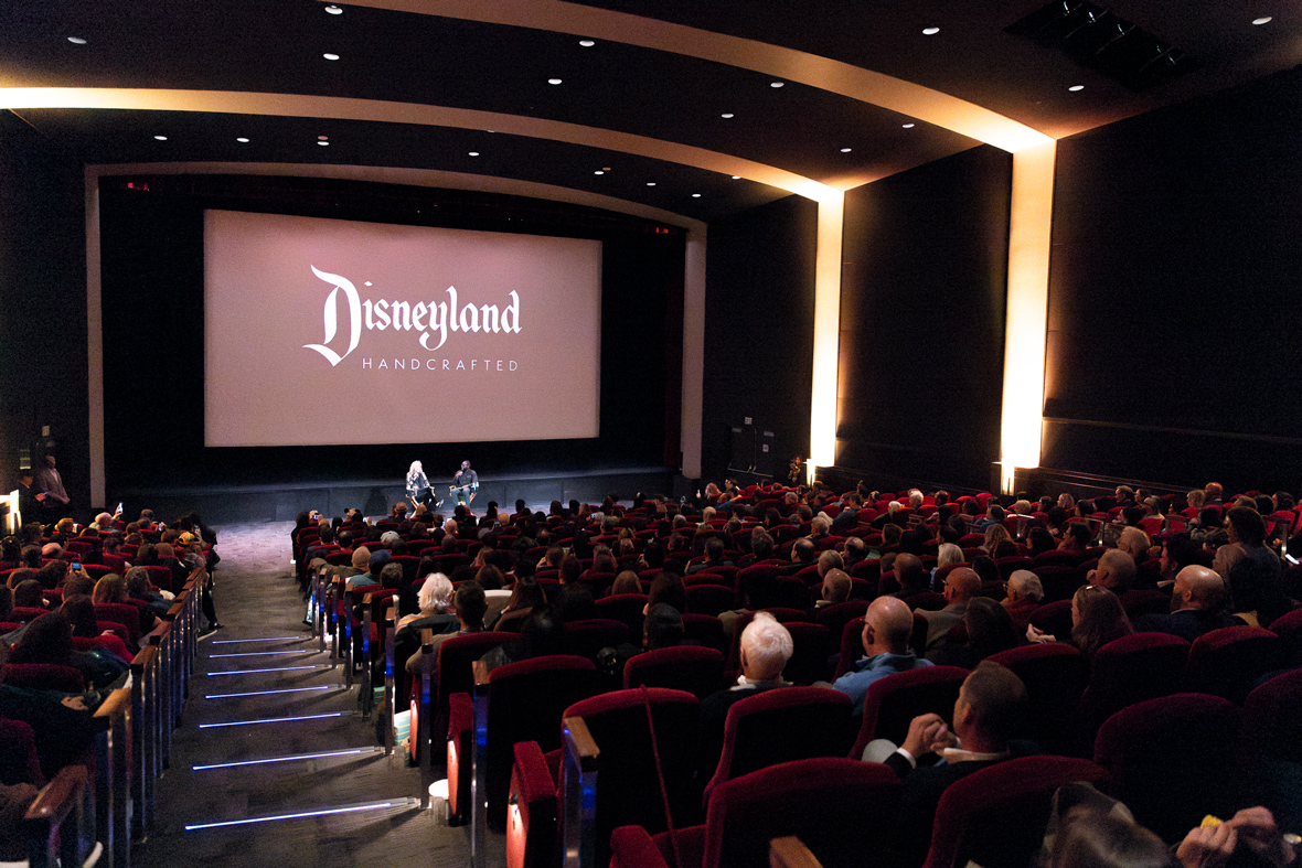 A wide view of Leslie Iwerks (left) and Juju Green (right) at the Walt Disney Studios&rsquo; Main Theater doing a Q&A before the premiere screening of Iwerks&rsquo; documentary film Disneyland Handcrafted. Both are sitting in director&rsquo;s chairs, holding microphones while talking. The film&rsquo;s logo can be seen on the screen above and behind them. In the foreground is the Main Theater audience.